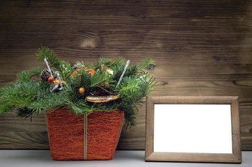 Empty blank photo frame with copy space and Christmas tree branches on burnt wooden wall background.