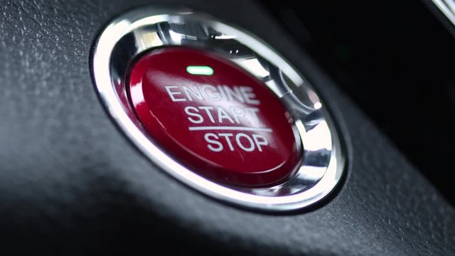 Pushing engine start button in a modern car closeup