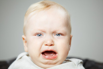 Disappointed blond baby boy cries hard portrait photo