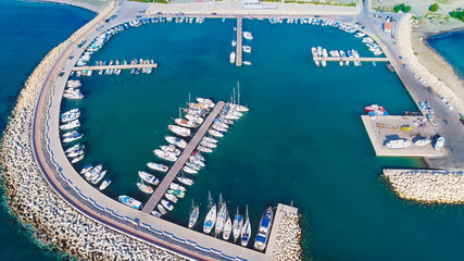 Aerial bird's eye view of Zygi fishing village port, Larnaca, Cyprus. The fish boats moored in the harbour with docked yachts and skyline of the town near Limassol from above. 