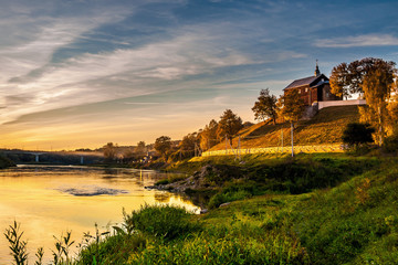 ancient orthodox church on the high bank in front of the river at beautiful sunset