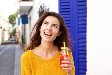 Close up pretty young lady holding juice looking away and smiling