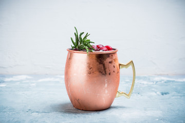 Cold christmas Moscow Mule cocktail in copper mug on the rustic background. Shallow depth of field. © maxandrew