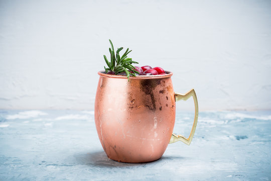 Cold christmas Moscow Mule cocktail in copper mug on the rustic background. Shallow depth of field.
