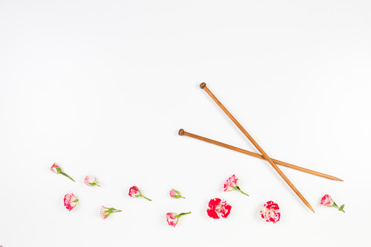 Wooden knitting needles and fresh roses on white background