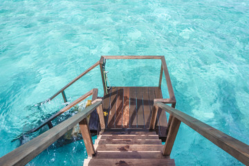 Fototapeta na wymiar Stair down to crystal clear ocean from water villa private balcony