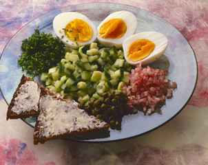 Eihälften mit fein gehacktem Gemüse und Schwarzbrotecken