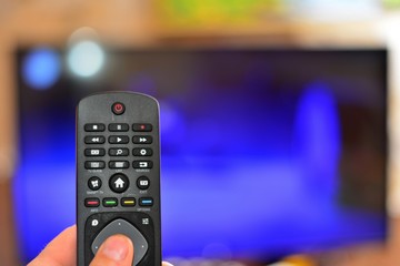 Young guy looking at camera while switching TV channels