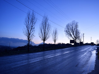 Blue lanscape of a road in winter after rain at dusk