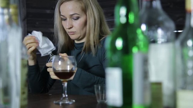 lonely barmaid clean the wineglass at bar waiting for clients.