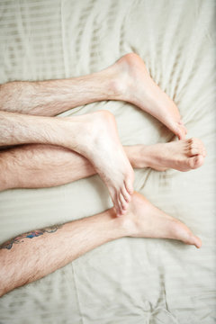 Bare feet and hairy legs of homosexual men during sleep