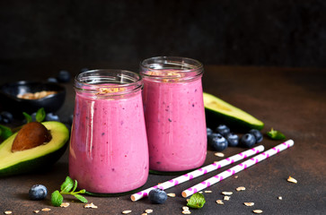 Organiik drink. Smoothies of yogurt with avocado, honey, blueberries and granola on a dark background. Easy snack.
