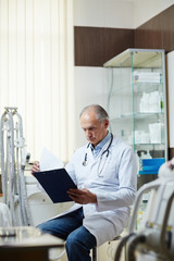 Naklejka na ściany i meble Contemporary clinician in whitecoat looking through medical documents in hospital