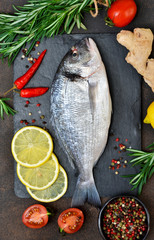 Food background. Fresh, raw Dorado with a swallow, lemon, avocado on a dark concrete background.