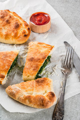 Italian food, closed pizza calzone with Spinach and Cheese, gray stone background, copy space