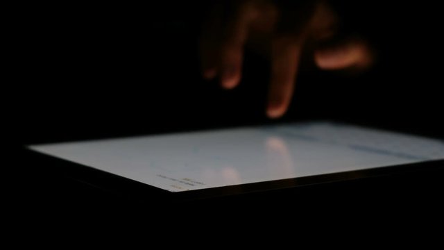 Hand write a message on the tablet in the dark close up, 4k.