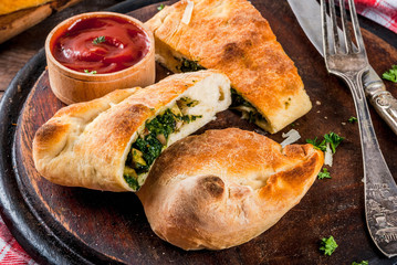 Italian food, closed pizza calzone with Spinach and Cheese, wooden background, copy space © ricka_kinamoto