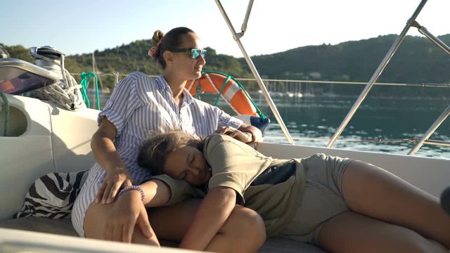 Mother and daughter relaxing while sailing boat on sea  
