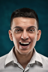 Close-up portrait of young handsome man showing happy emotions on dark blue background