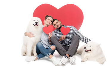 Obraz na płótnie Canvas happy couple with samoyed dogs and paper hearts on white, valentines day concept