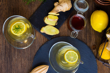 Glass cup of hot tea with mint, honey, ginger and lemon on dark background.