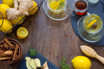 Glass cup of hot tea with mint, honey, ginger and lemon on dark background.