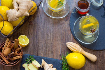 Glass cup of hot tea with mint, honey, ginger and lemon on dark background.