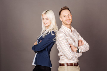 Business people smiling and  standing back to back with arms crossed ion dark  background