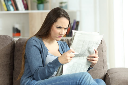 Angry woman reading a newspaper on a couch