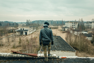 a man with tactical equipment standing on the top of abandoned building