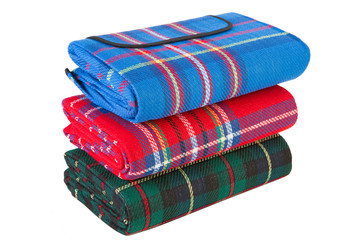 three picnic mats lie in a pile on a white background