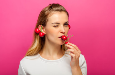 Woman over pink background eating cherry fruit