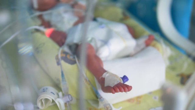 A newborn baby lying inside a crib at a hospital. 