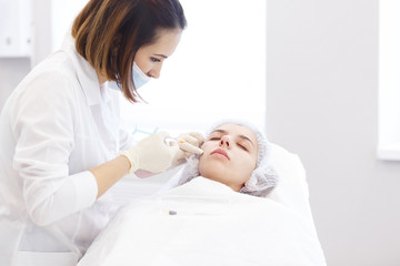 Obraz na płótnie Canvas Hardware and Injections cosmetology. Process of facial beauty injections, biorevitalization of female face procedure in a beauty clinic . Cosmetologist works with patient in a white cosmetology office