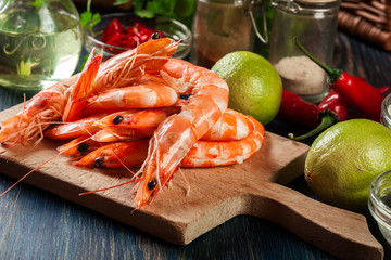 Selection of shrimp ready for frying with onion, garlic, chili and lime on cutting board