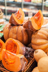Pumpkins on a stall at organic farmers grocery store. Ripe cut in a pieces  pumpkins at market