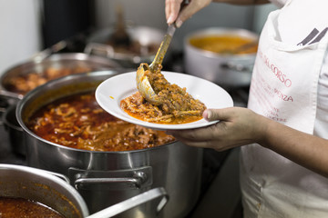 The cook puts tripe in the plate