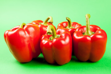 Group of five fresh and healthy sweet red pepperson green background