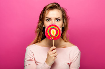 Beautiful young woman with big lollipop on pink background