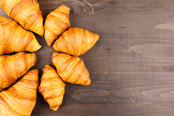 Mini and maxi croissants lying on wooden table. Close up