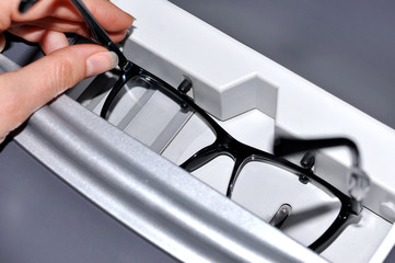 Female optician measuring and preparing glasses on the digital device in optical store 