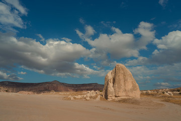 Fototapeta na wymiar panorama of a desert valley with a large stone and floating clouds