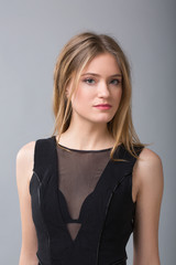 Fototapeta premium Portrait of Attractive blonde woman in a black dress on a background of a gray wall.