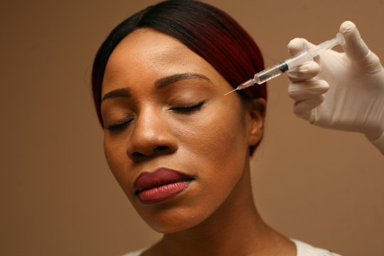 Portrait of African woman apply skin filers. Close up.