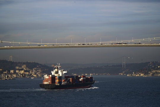 A container ship is passing under The Bosphorus Bridge in a sunny day at Istanbul. Also The Fatih Sultan Mehmet Bridge is visible at the background too.