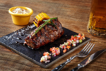 Grilled tenderloin Steak roastbeef and mushrooms sauce on black cutting board and glass of beer on...