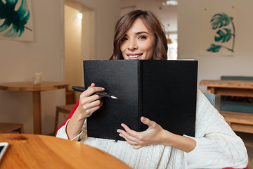 Portrait of a happy woman holding blank cover notepad