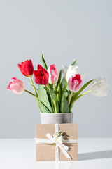close-up view of beautiful blooming tulip flowers in vase and envelope on grey