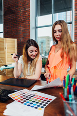 Fototapeta premium Creative female interior decorator working with a customer in her office choosing colors for a new design using color charts