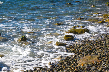 rocky sea shore with pebble beach, waves with foam